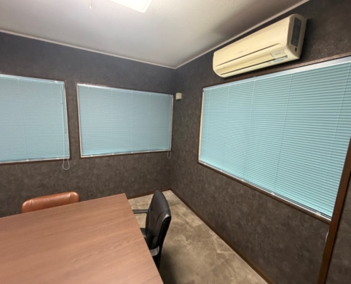 埼玉県八潮市の事務所会議室リフォーム後の様子。ダークグレーの壁面と新しいブラインドで統一された空間。